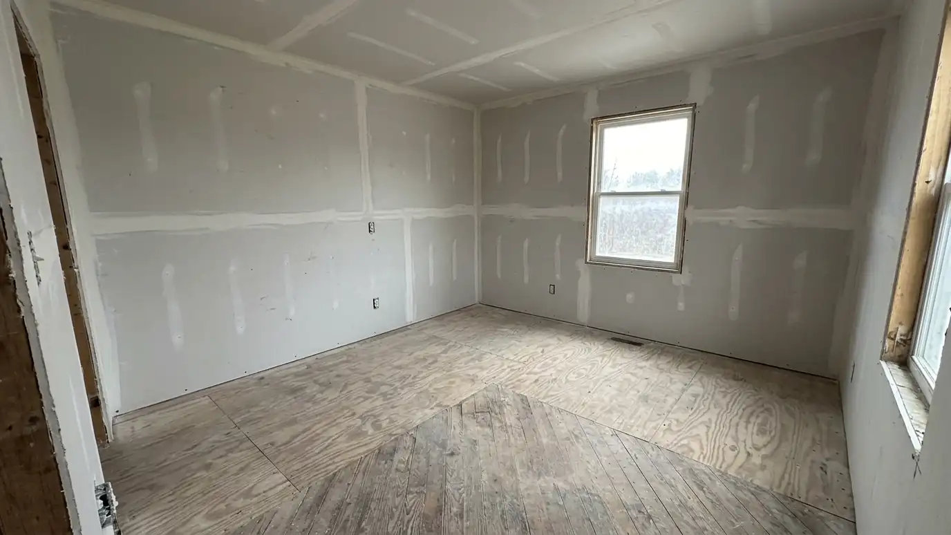 After: A gutted room full of debris, then a broom-clean room with new drywall | Music City Roll Off After: a gutted room with a broom-clean floor and fresh new drywall on the walls